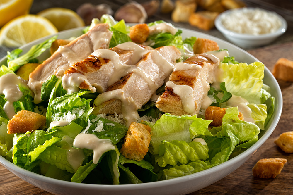 Una gustosa Caesar salad con lattuga, pollo, crostini e salsa al formaggio