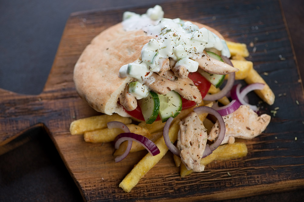 (La pita ripiena con carne di pollo e verdure, accompagnata dalla salsa tzatziki, è un piatto greco gustosissimo!)