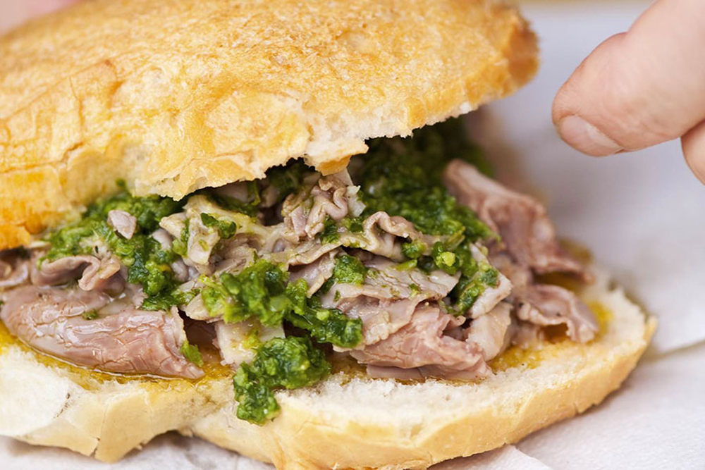 Il panino ripieno con lampredotto accompagnato da salsa verde è un must quando si mangia cibo da strada a Firenze!