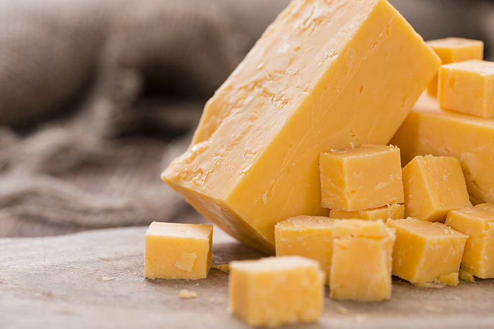 formaggio cheddar su tagliere tagliato a cubetti