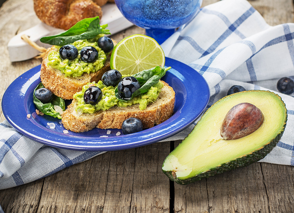 bruschette di pane croccante con crema di avocado, mirtilli e lime