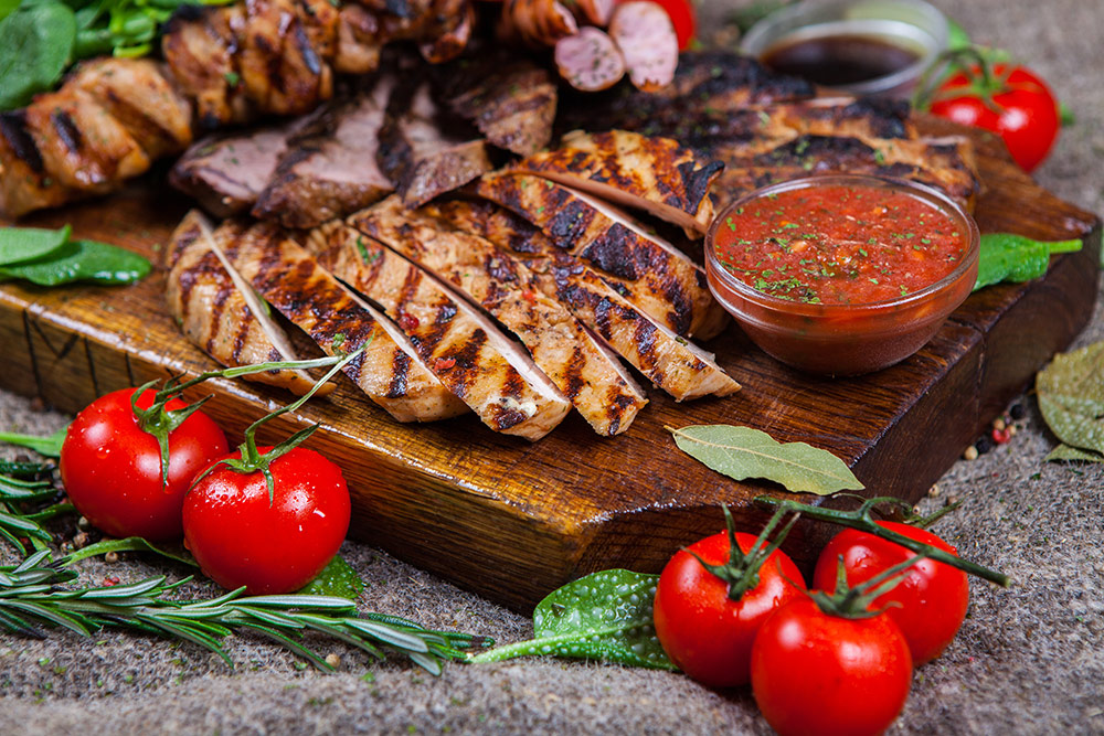 Carne bianca di pollo al barbecue con pomodorini, cipolla e foglie di rosmarino, salvia e basilico